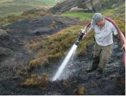 Photo B8.10 A Ranger assisting with damping down hot spots at a fire in the Peak District